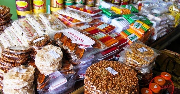 Top left: A Pasalubong store selling specialty products from Bicol; Top right: Various pasalubong items in a Filipino store; Bottom left: Oleh-oleh store in Bali; Bottom right: Oleh-oleh specialty products from Makassar