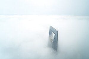 Top of a very tall building peeking out from clouds in Shanghai