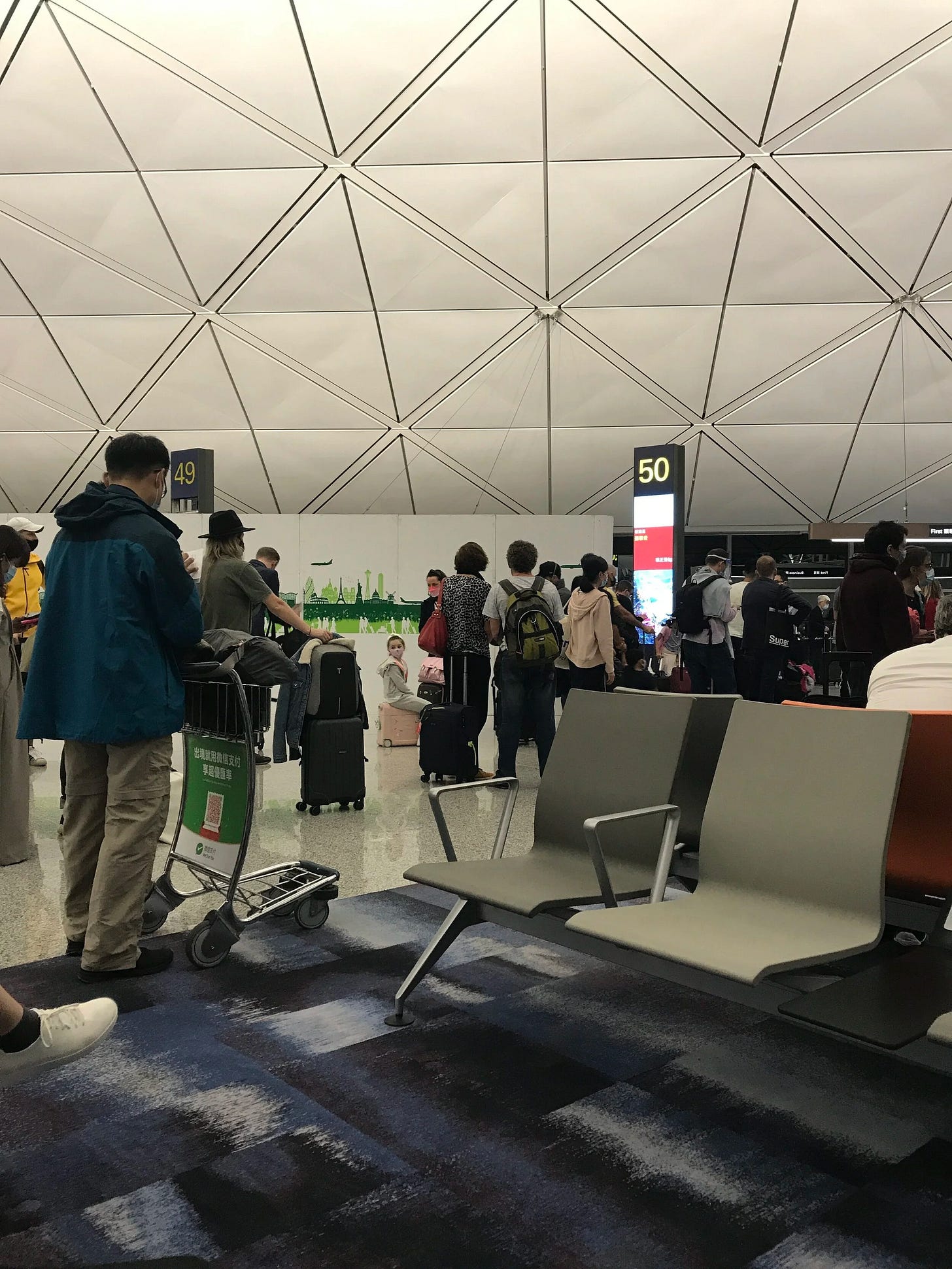 A decent amount of people waiting to board the flight from Hong Kong to Zurich A decent amount of people waiting to board the flight from Hong Kong to Zurich