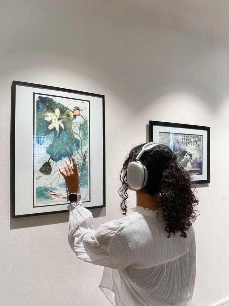 This may contain: a woman wearing headphones looking at artwork on the wall