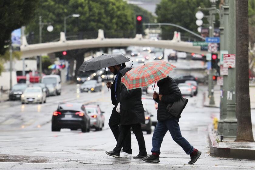 LOS ANGELES, CA - MARCH 11: People walk with umbrellas to hide from the rain in downtown Los Angeles, CA on March 11, 2025. .(Allen J. Schaben / Los Angeles Times)