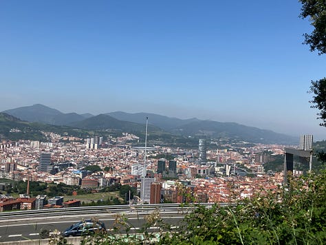 a roadside yellow arrow marking path, the soda machine on route, a view of descent into Bilbao