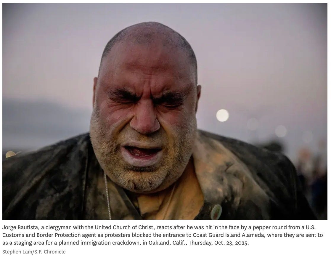 May be an image of one or more people and text that says 'Jorge Bautista, a clergyman with the United Church of Christ, reacts after he was hit in the face by a pepper round from U.S. Customs and Border Protection agent protesters blocked the entrance to Coast Guard Island Alameda, where they are sent to as staging area for planned immigration crackdown, in Oakland, Calif., Thursday, Oct. 23, 2025. Stephen Lam/S.F. Chronicle'