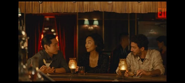 This may contain: three people sitting at a bar with candles in front of them and one person holding a drink