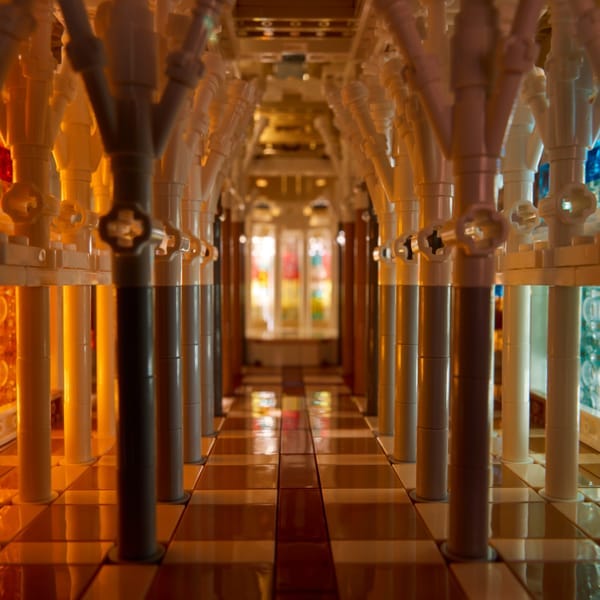 An interior view inside the LEGO Architecture Sagrada Família set showing a brick corridor featuring vibrant red, orange, and blue stained-glass patterns.