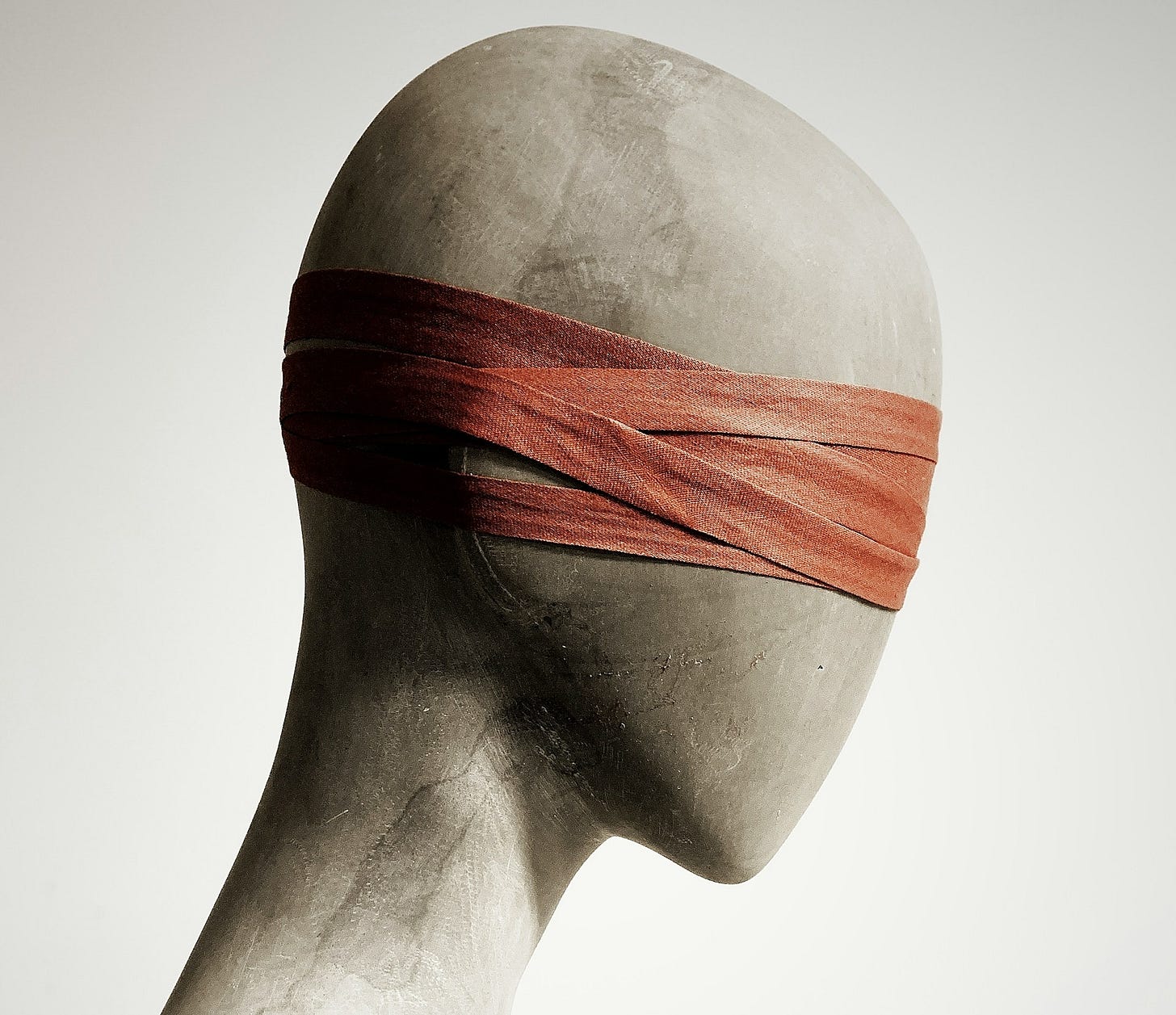 white mannequin with a red band on it's head illustrating blinding effect of bullshit