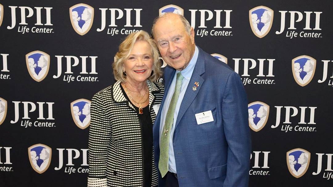 two people in front of JPII banner