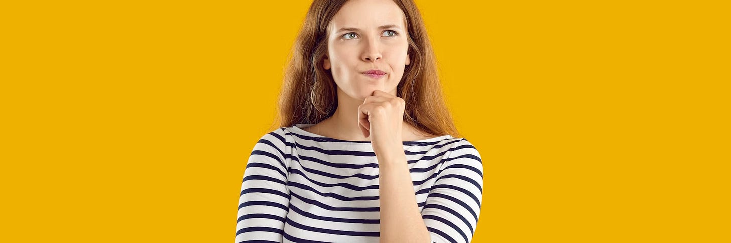 Person with long red hair in a black-and-white striped shirt holds their chin and looks up thoughtfully against a solid yellow background. Person with long red hair in a black-and-white striped shirt holds their chin and looks up thoughtfully against a solid yellow background.