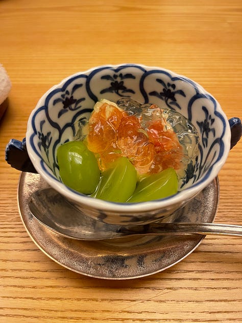 A collage of nine photos from Japan: a man in traditional kimono performing a tea ceremony; a tray of delicate kaiseki dishes with seasonal ingredients; a serene temple garden surrounded by moss and trees; a tatami room with sliding shoji doors; a mountain view with Mount Fuji in the distance; a bowl of Japanese dessert with green grapes and jelly; a Shinto wedding procession under a red umbrella; a moss-covered stone Buddha statue in a forest; and misty temple grounds framed by lush greenery.