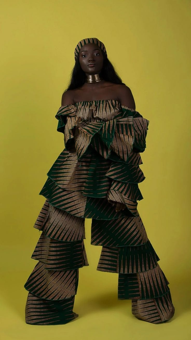 This may contain: a woman in a green and gold dress standing against a yellow background with her hands on her hips