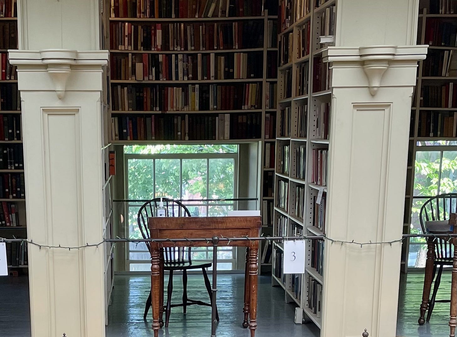 A wooden chair and wooden desk in an alcove made of floor-to-ceiling bookshelves A wooden chair and wooden desk in an alcove made of floor-to-ceiling bookshelves