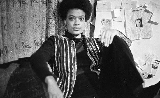 A black and white portrait of Toni Cade Bambara in a striped vest, seated. A black and white portrait of Toni Cade Bambara in a striped vest, seated.
