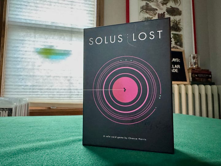 Solus: Lost, a card drawing, sci-fi, boss battler. The box is all black with pink design flourishes.