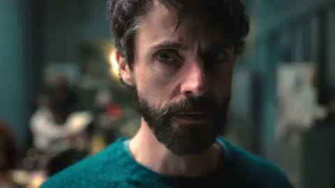 Netflix Close up of a man wearing a green jumper staring off to the right of the camera.