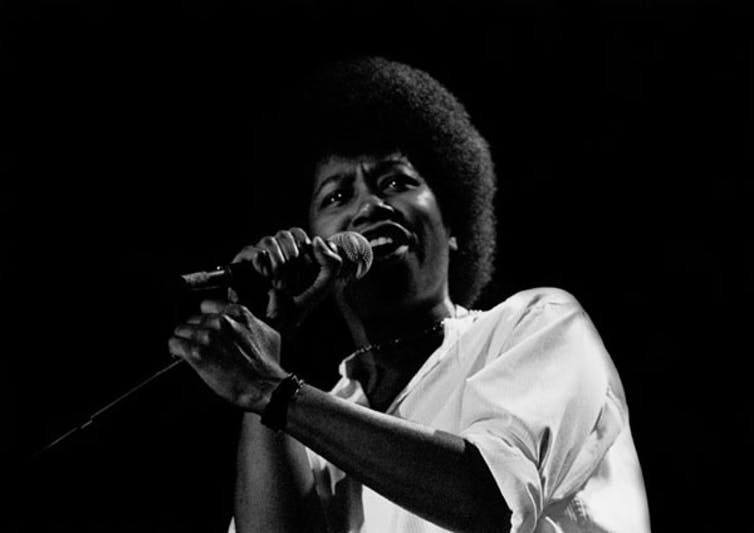 Black woman in white t-shirt singing into a microphone. Black woman in white t-shirt singing into a microphone.