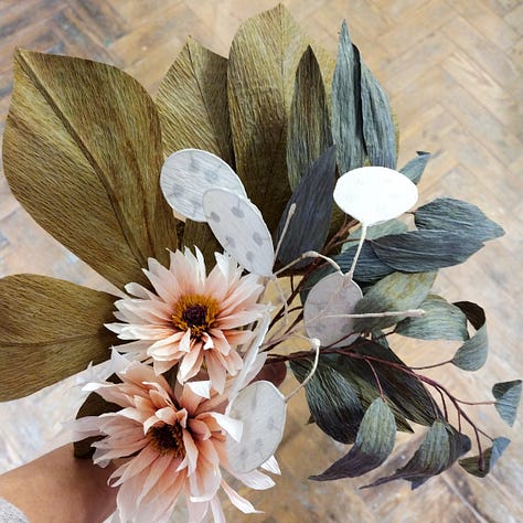 A selection of paper flowers including passion flowers, bindweed, foliage and dahlias