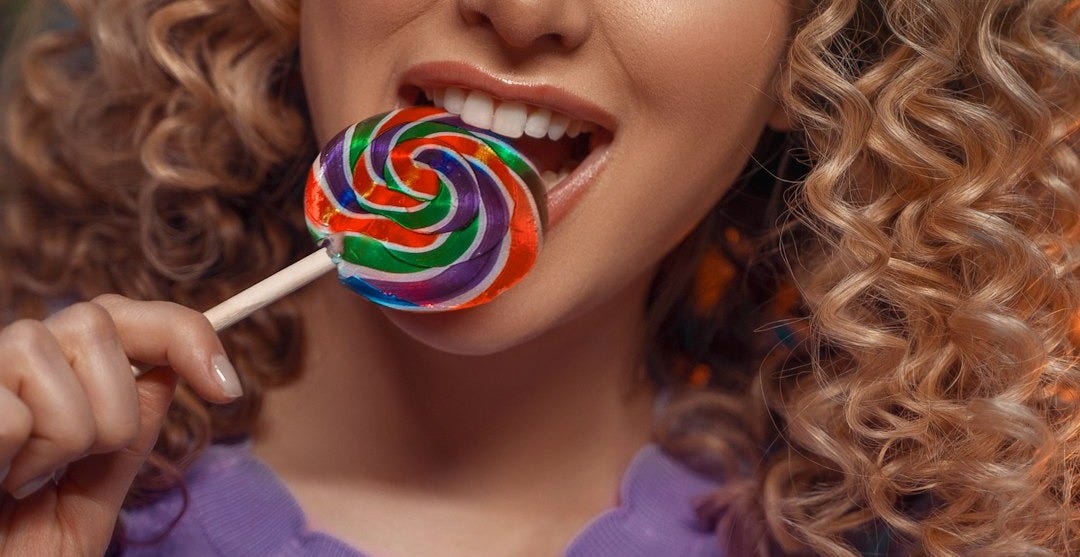 a woman holding a lollipop in her mouth a woman holding a lollipop in her mouth
