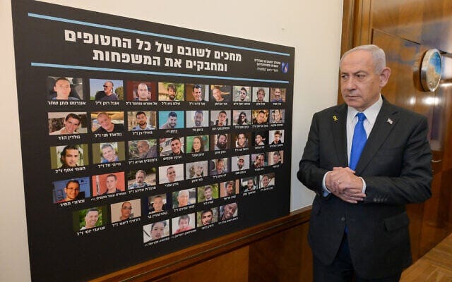 Prime Minister Benjamin Netanyahu pictured next to a placard showing the 48 hostages held in Gaza, prior to a cabinet meeting on October 9, 2025, to approve a deal formulated by US President Donald Trump for their release, the freeing of large numbers of Palestinian security prisoners, a partial IDF withdrawal and a Gaza ceasefire (Maayan Toaf / GPO)