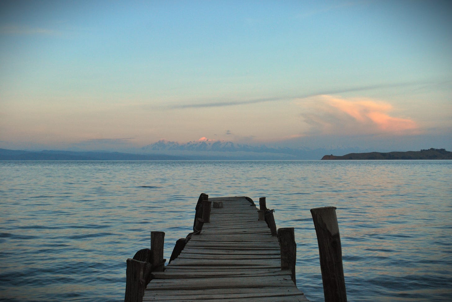 The photo shows sunset on the Isla del Sol, an island in the Lake Titicaca in Bolivia. In the foreground, there is a landing stage. 