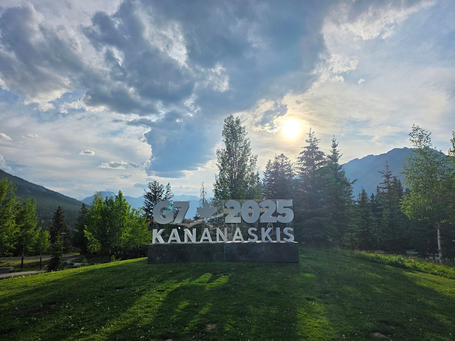 G7-Kananaskis sign on a small hill under a cloudy sky, in front of the rockies