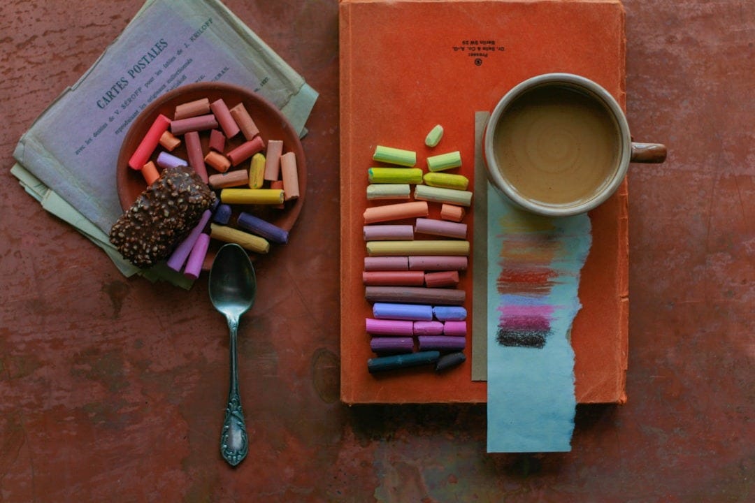 a cup of coffee next to a box of crayons