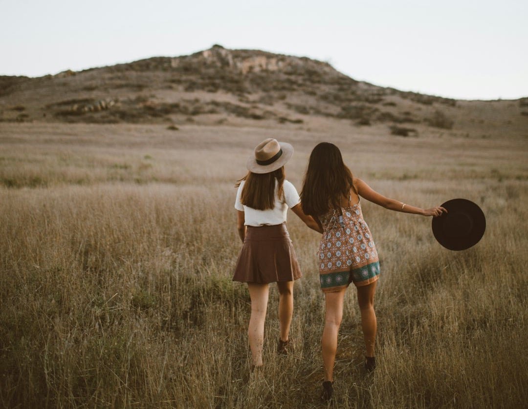 two women walking around near mountain at daytime two women walking around near mountain at daytime
