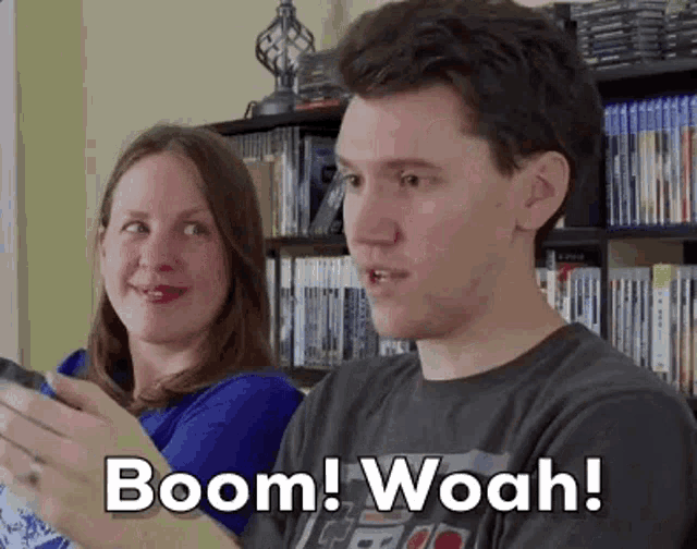 a man and a woman are playing a video game and the man is saying boom woah .