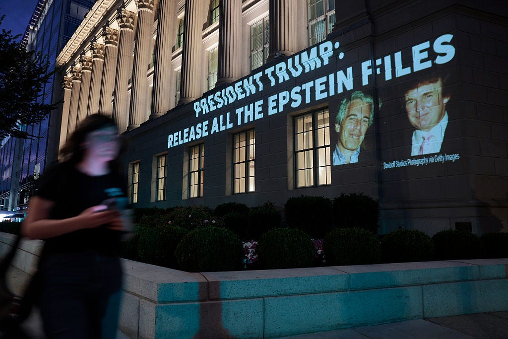 A person walks by an image of U.S. President Donald Trump and Jeffrey Epstein, along with the words “President Trump: Release All the Epstein Files”, projected onto the U.S. Department of Commerce headquarters