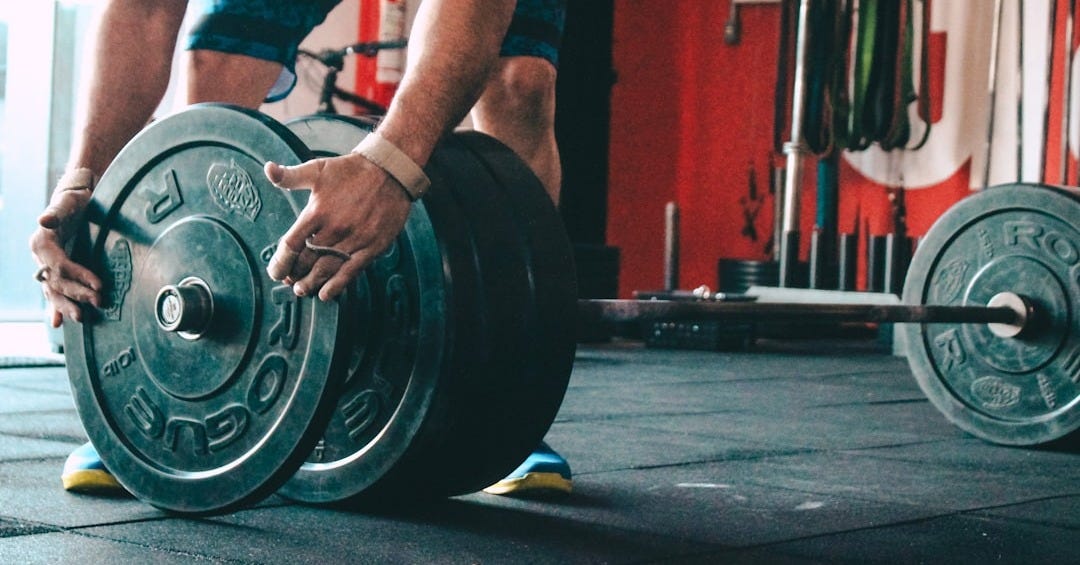 man placing weight plate on barbell