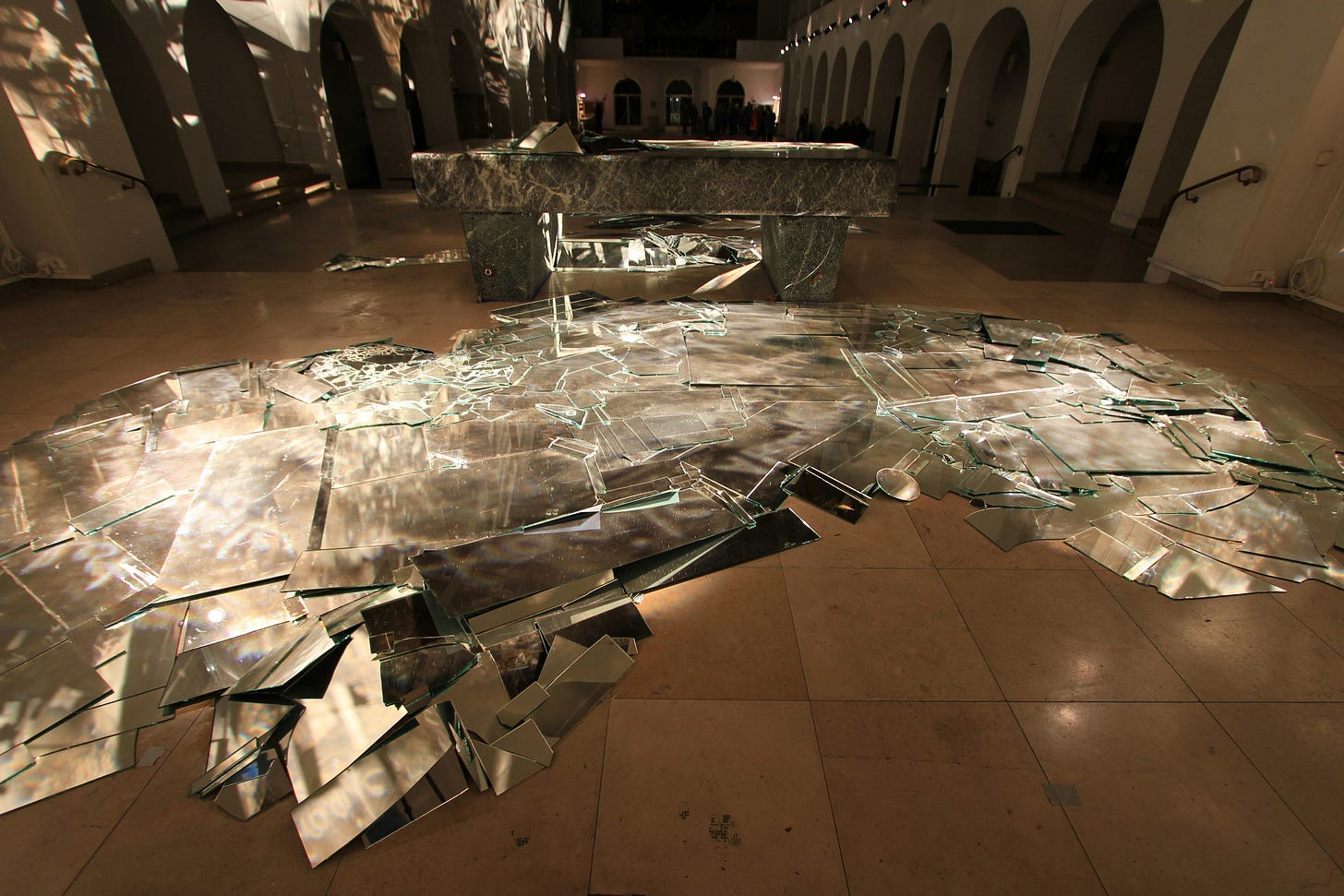 Photo of a museum exhibit of an array of broken glass on a tile floor