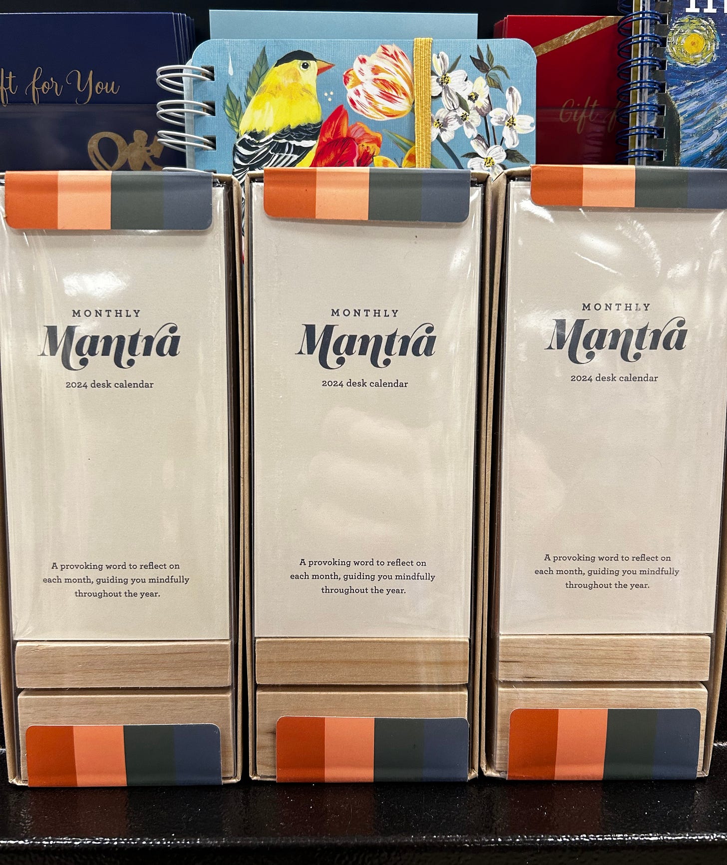 The spines of three desk calendars side by side, each of which reads "Monthly mantra: 2024 desk calendar"