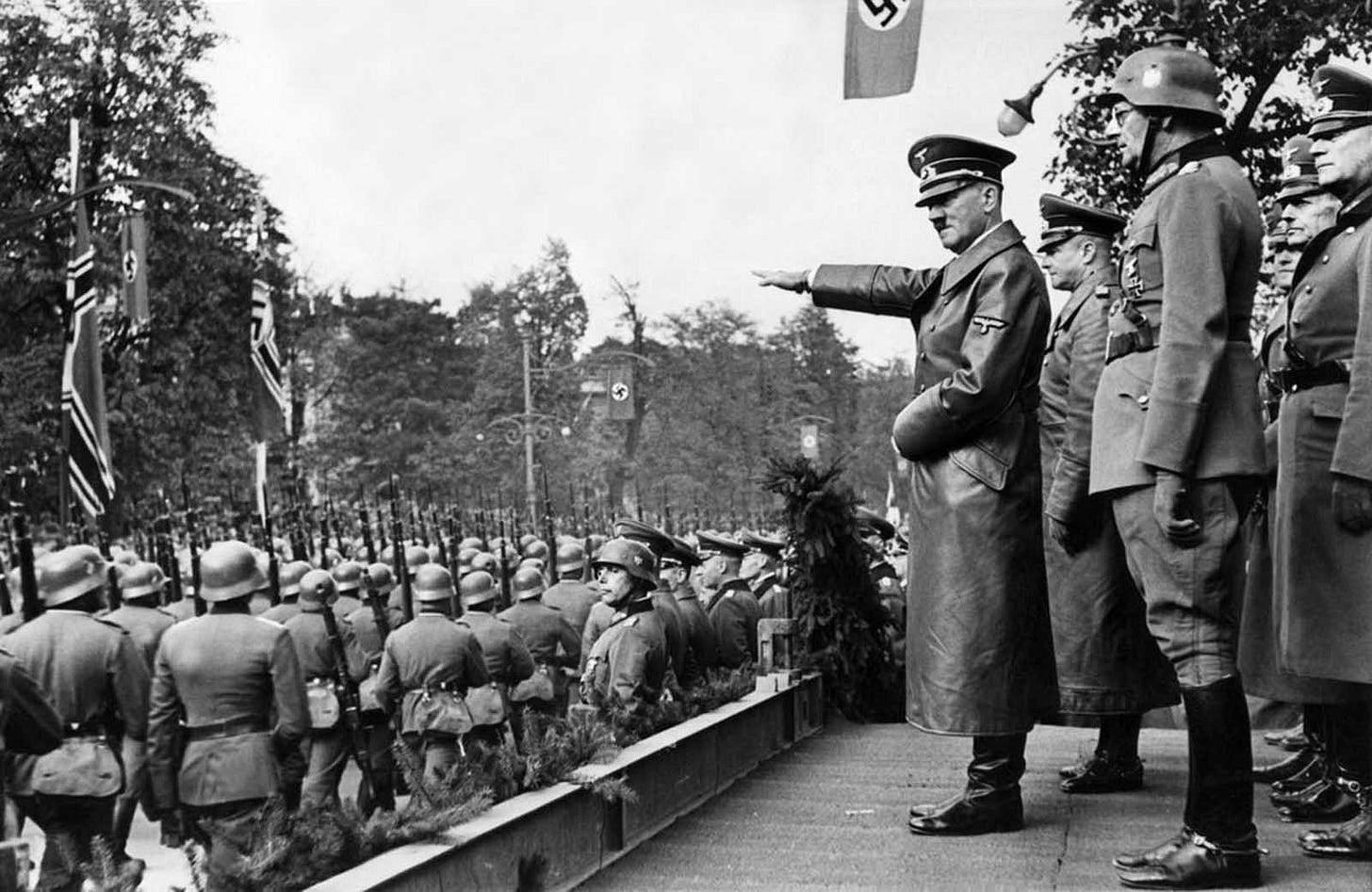 Adolf Hitler salutes parading Wehrmacht troops in Warsaw on October 5, 1939, following the German invasion, with senior generals like von Brauchitsch and Keitel behind him. Adolf Hitler salutes parading Wehrmacht troops in Warsaw on October 5, 1939, following the German invasion, with senior generals like von Brauchitsch and Keitel behind him.