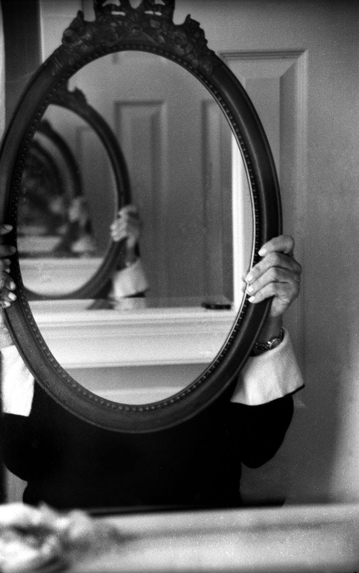 This may contain: a woman holding up a large mirror to her face in front of a bathroom sink