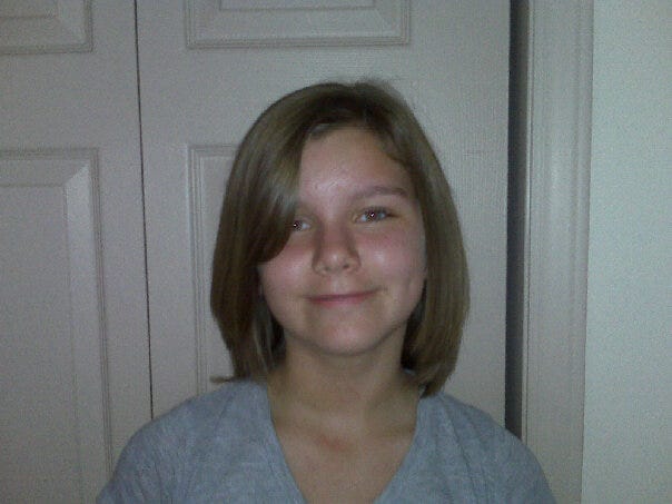 A tween girl with short hair smiling in front of a white backdrop.