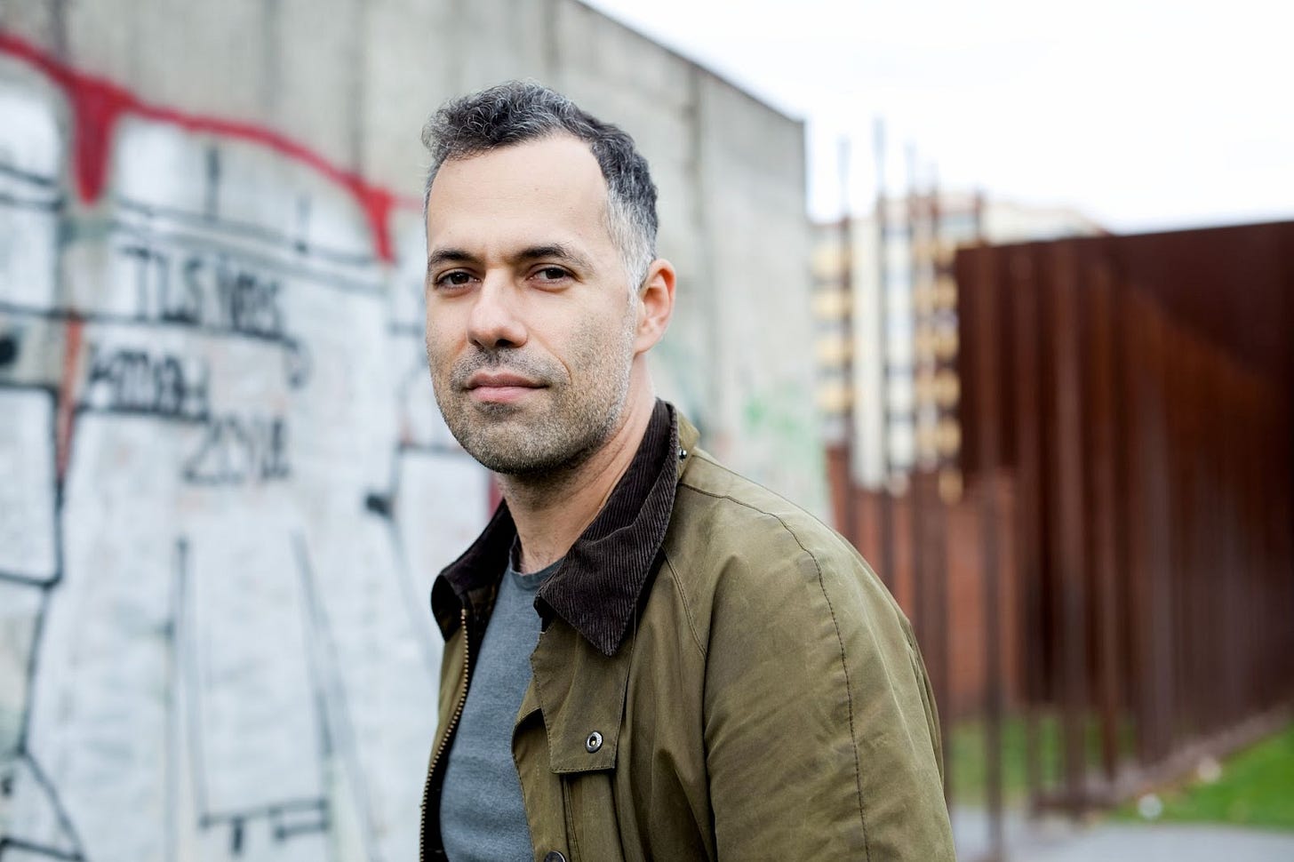 Michael Idov standing before wall of graffiti