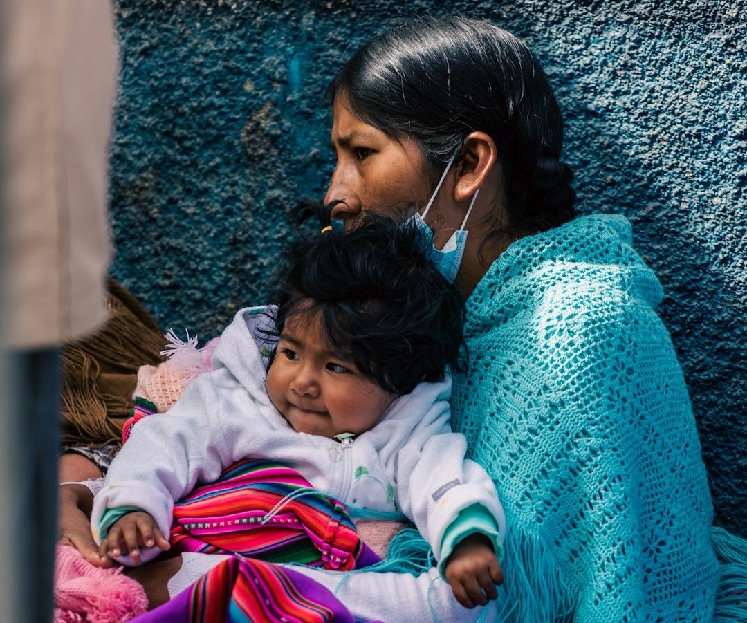 a woman and child are sitting against a wall