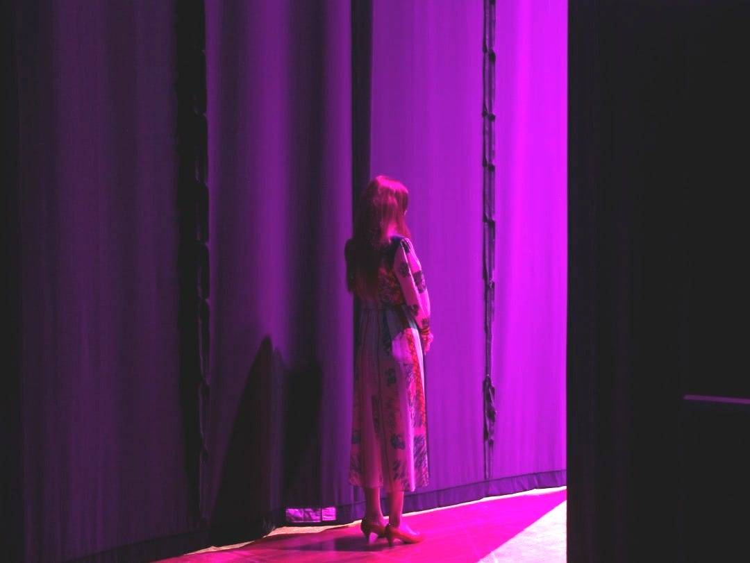 a woman standing in front of a purple curtain a woman standing in front of a purple curtain