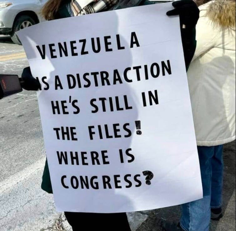 Outdoor protest photo of a person holding a sign: “Venezuela is a distraction… He’s still in the files! Where is Congress?”