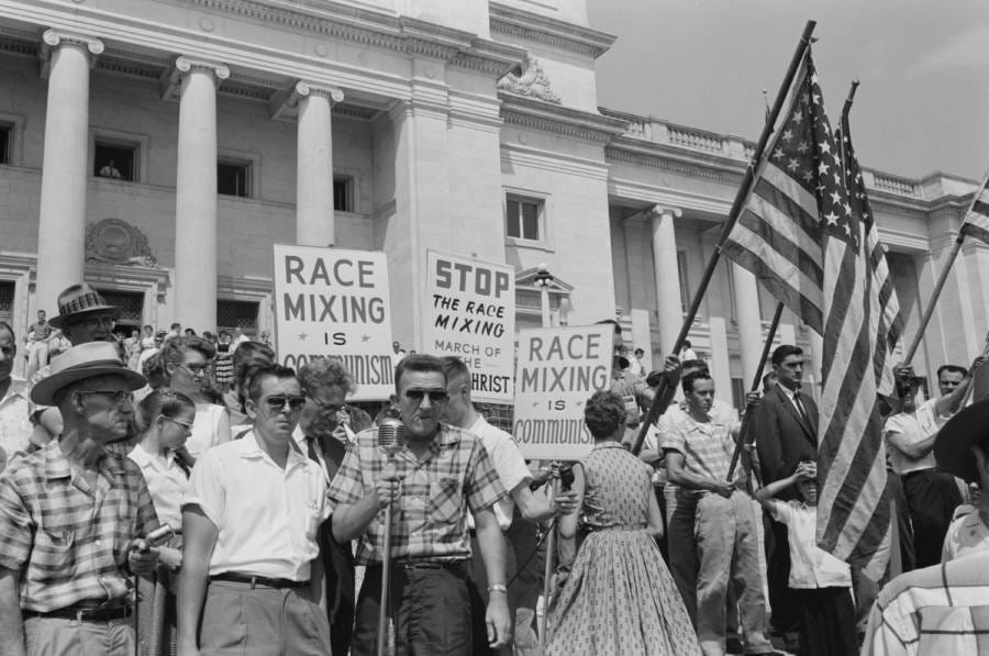 A bunch of white racists protest integrated schools. Their reason is that it is communism.