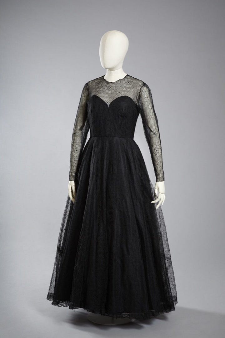 1) Classic black-and-white portrait of Gluck in a loose white shirt/smock, looking down and to the side. Their expression is thoughtful, with shadows adding depth. They have short dark hair, and they are holding a cigarette in their right hand. There is a dark shirt sticking out from under the larger shirt, with both collars sticking up. 2) A white mannequin displays a vintage, cream-colored linen shirt/smock with a black collar and buttoned cuffs, evoking a classic, timeless style. It's positioned in the same style Gluck was wearing it in the previous photo, including the collars sticking up. The mannequin head is also looking to the side, like Gluck was. 3) A pair of vintage brown leather shoes with buckles and low heels on a neutral background, conveying a sense of timeless style and craftsmanship. 4) Five vintage dresses/gowns hang on a black clothing rack with a small jacket. Patterns include floral, paisley, and abstract designs, evoking a nostalgic and elegant feel. 5) A white mannequin displays an elegant black evening gown with a lace overlay. The dress features long sleeves and a floor-length skirt, conveying sophistication.