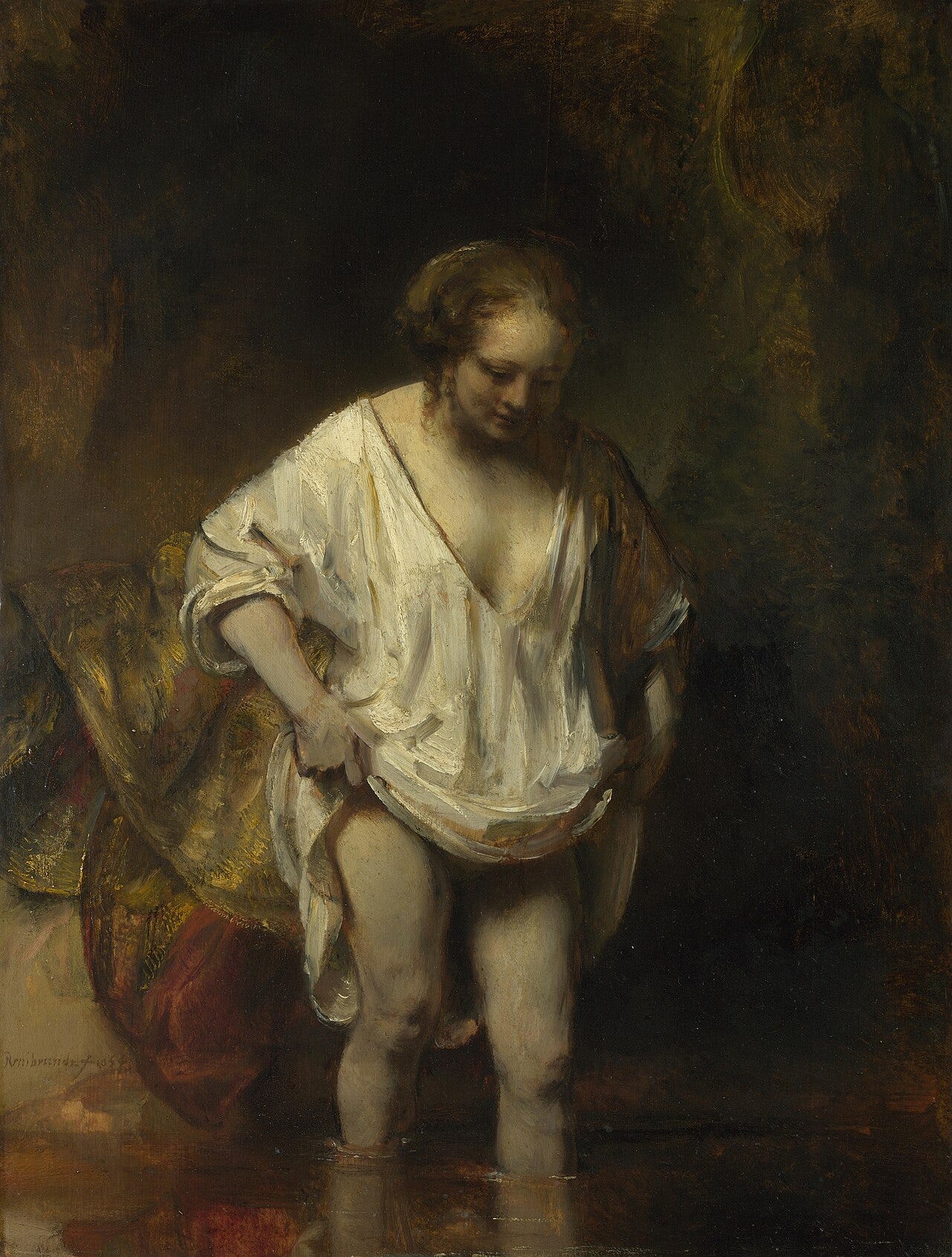 A Woman Bathing in a Stream by Rembrandt: a woman in a white shift wades into a dark stream
