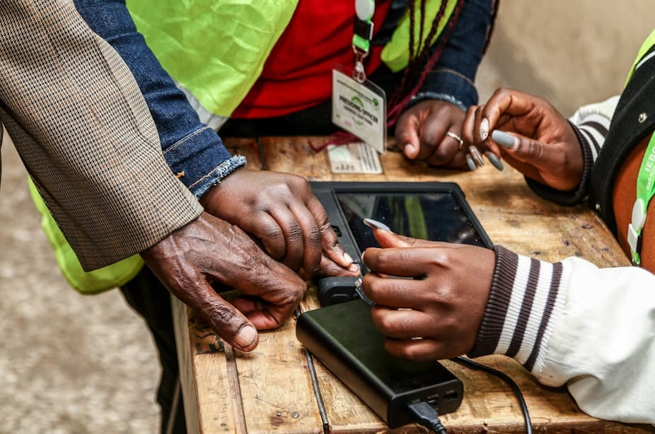 A person's finger is held against a scanner on a rough wooden table A person's finger is held against a scanner on a rough wooden table