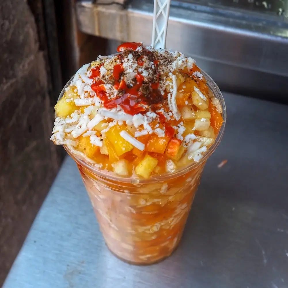 A plastic cup filled with fruit and orange juice