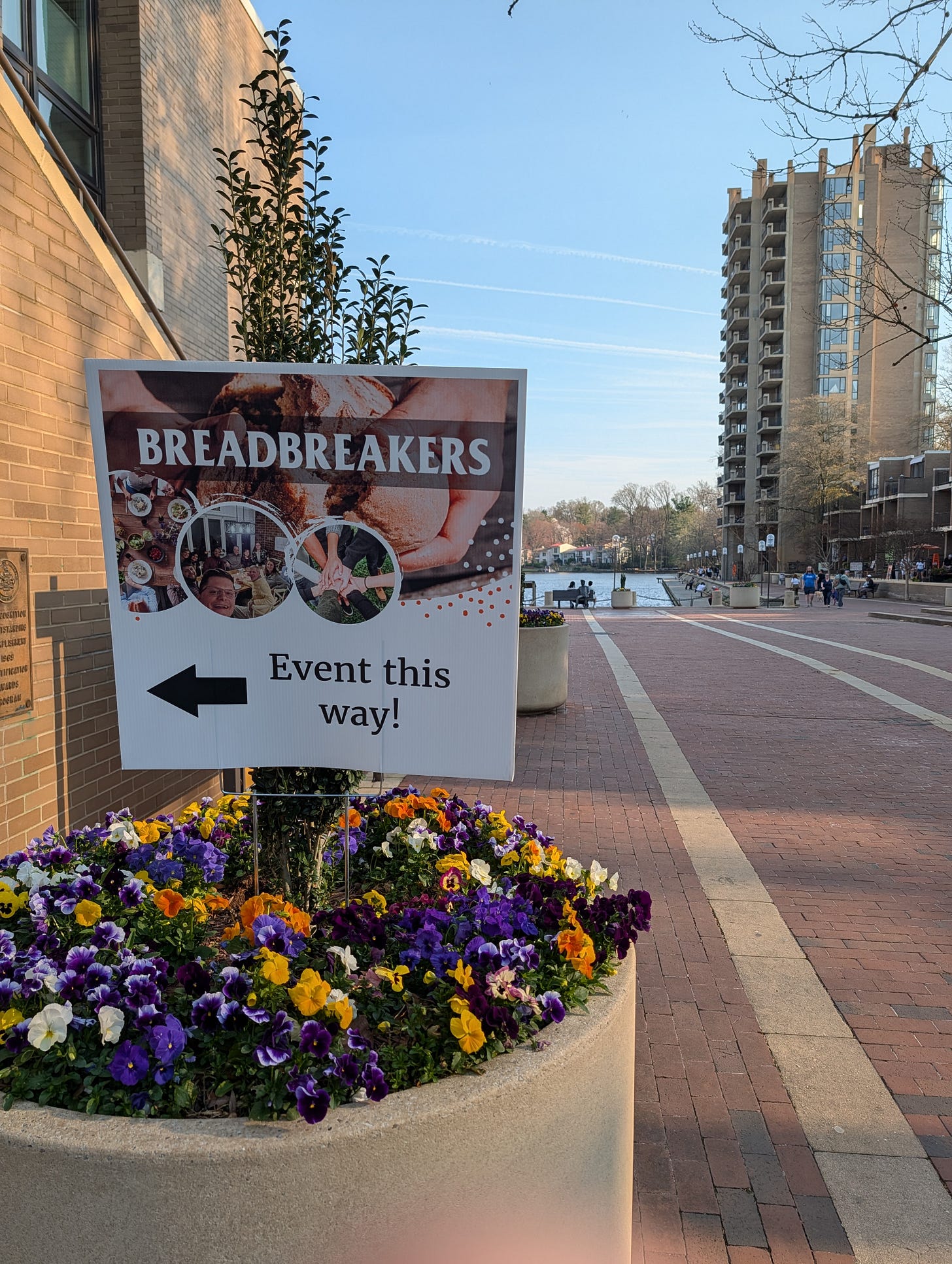 BreadBreakers sign in a beautiful blooming flower pot with Lake Anne behind it