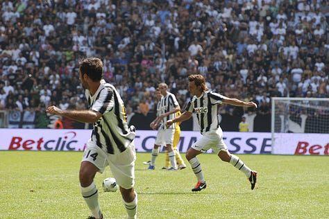 Juventus vs Parma, September 11, 2011: Arturo Vidal celebrates scoring on his debut, Juventus players embrace, fans erupt in celebration, Del Piero and teammates on the pitch, and Gianluigi Buffon giving a thumbs up during the opening match at Juventus Stadium.