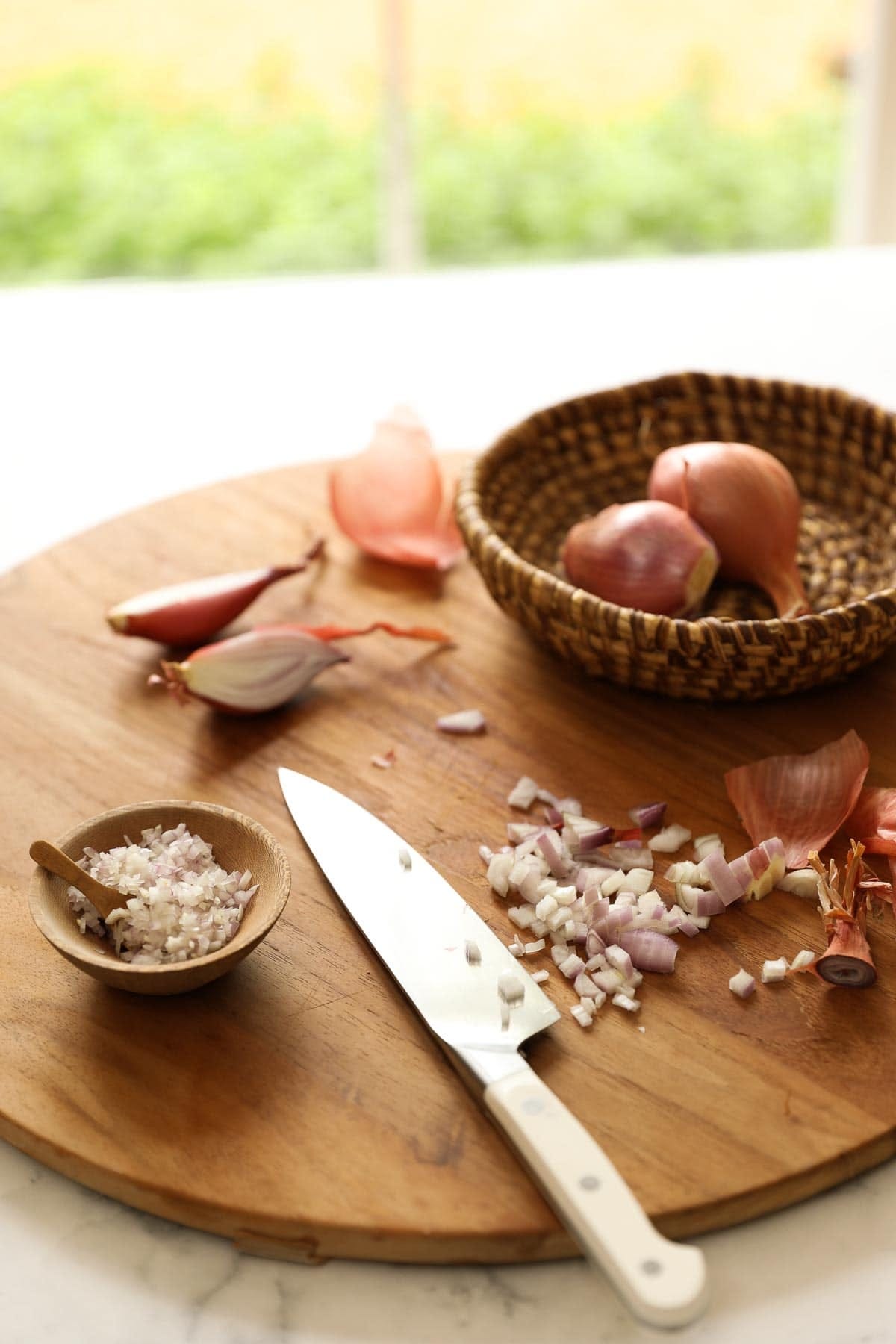 Chopped shallots on a board with a knife.