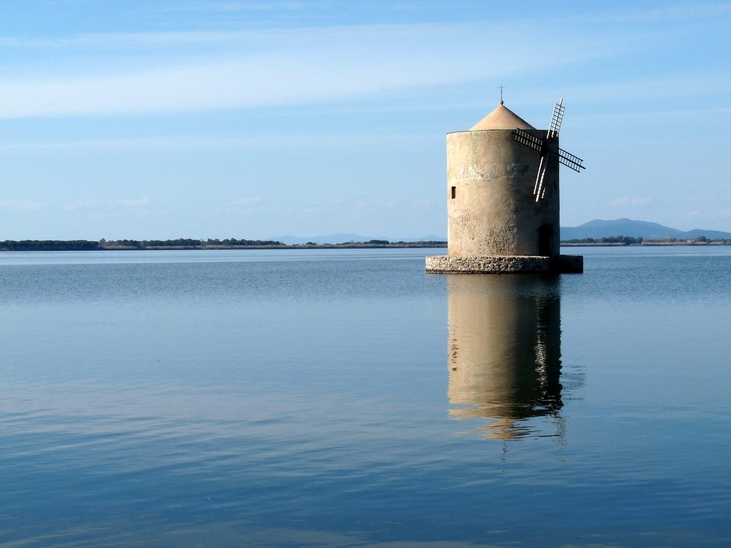 An ancient windmill set in the middle of a lagoon An ancient windmill set in the middle of a lagoon