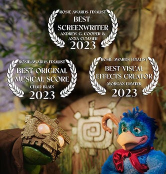 Puppets of a blue bird creature and a green reptilian stand before an ancient monolith. Puppets of a blue bird creature and a green reptilian stand before an ancient monolith.