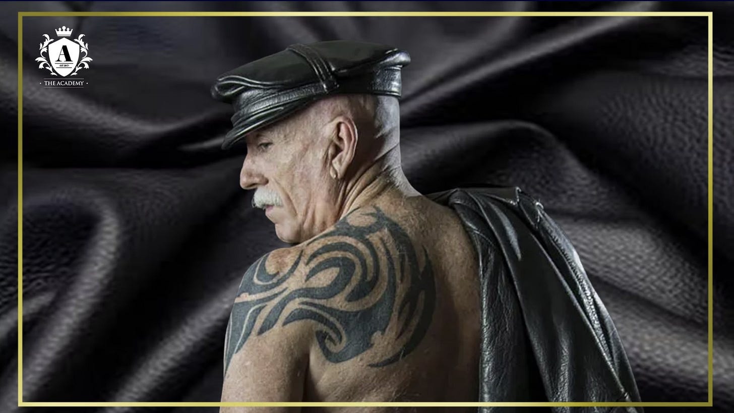 A photograph or Race Bannon in leather cap and leather jacket over his shoulder in front of a leather background. (Photo by Alex Ray.)