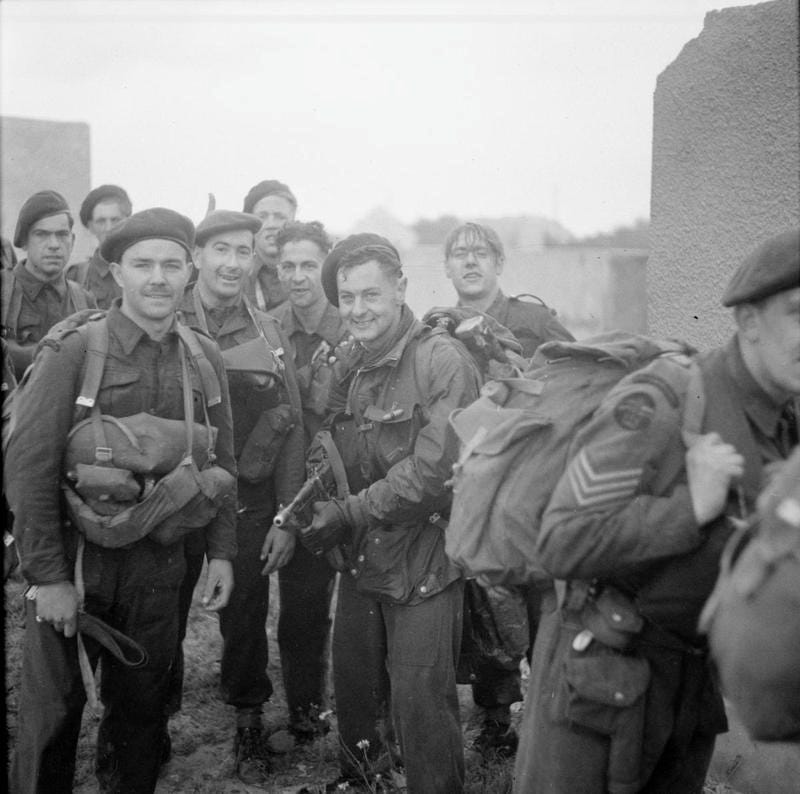 A black and white photo of a squad of British special forces commandos smiling for a photo during a pause in fighting on June 6, 1944 in the vicinity of Sword Beach, Normandy, France. A black and white photo of a squad of British special forces commandos smiling for a photo during a pause in fighting on June 6, 1944 in the vicinity of Sword Beach, Normandy, France.